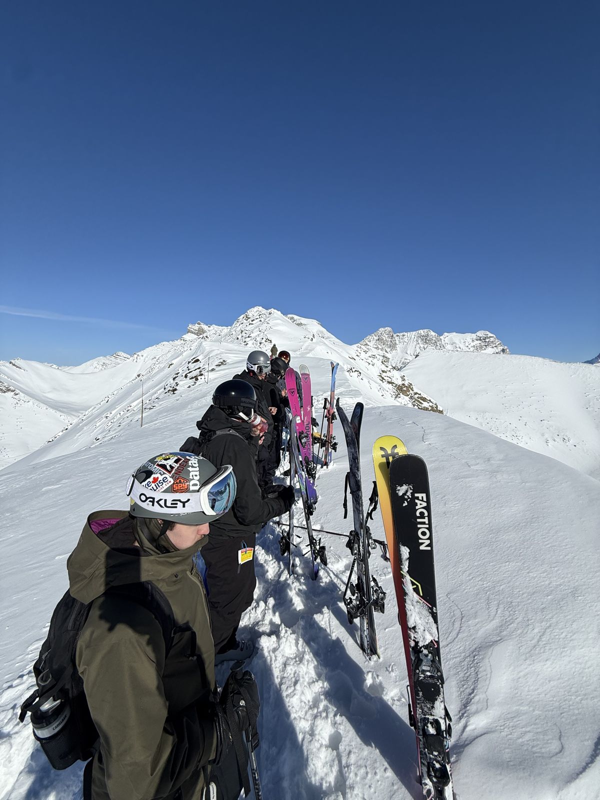 Skiers lined up on a mountain ridge