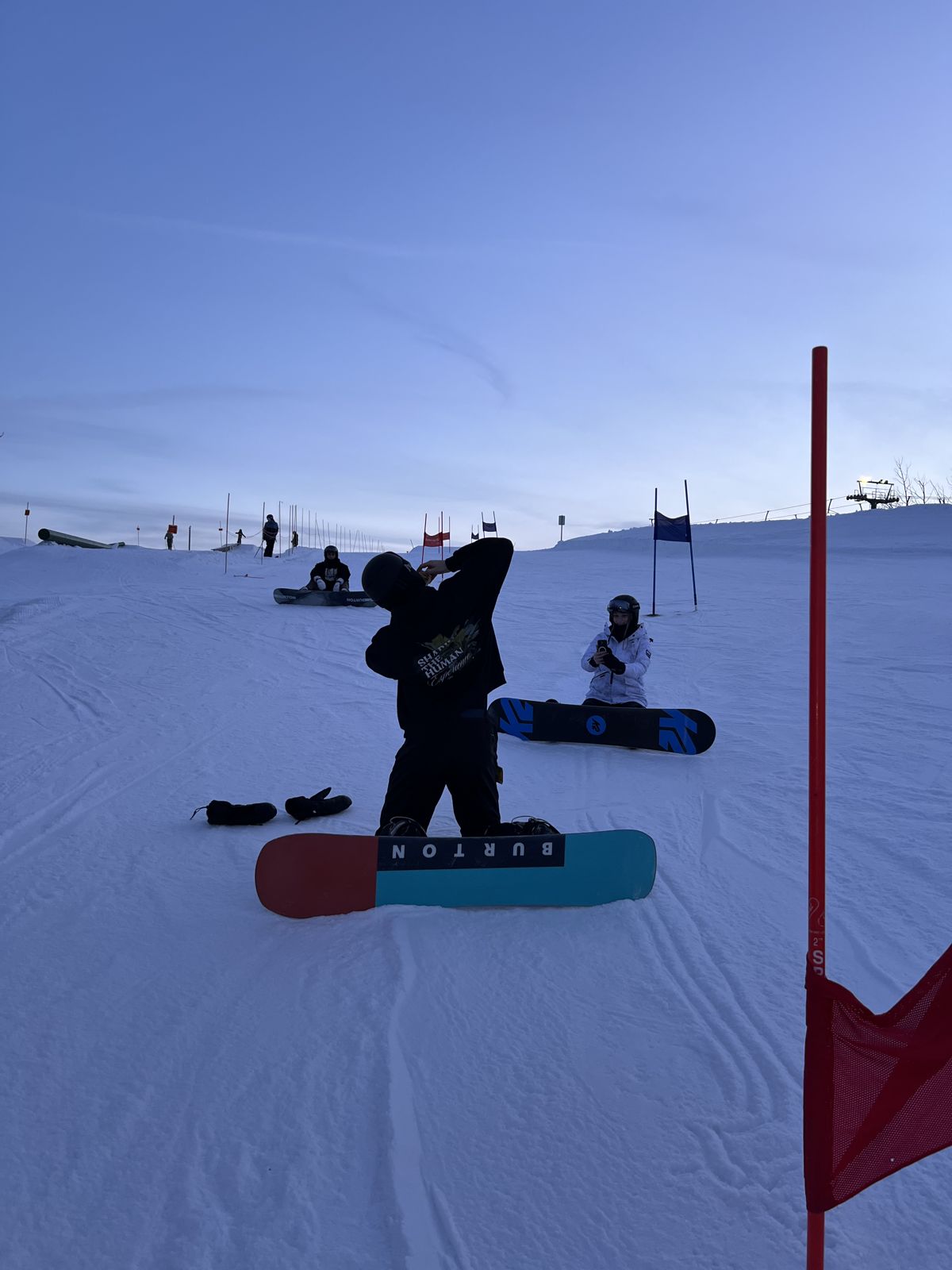 Snowboarders strapping in on the hill